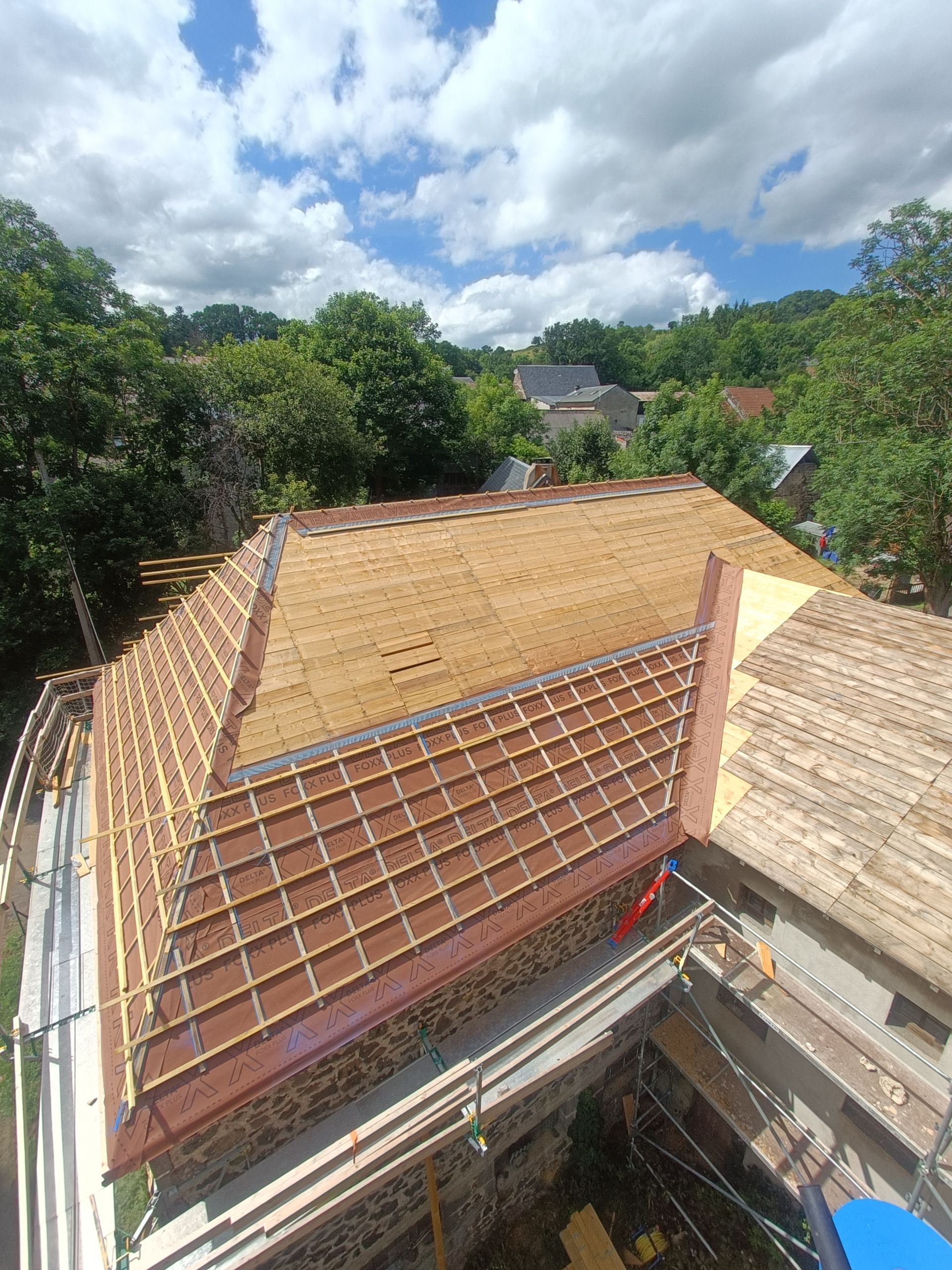 Toiture en construction avec charpente en bois et sections de tuiles.