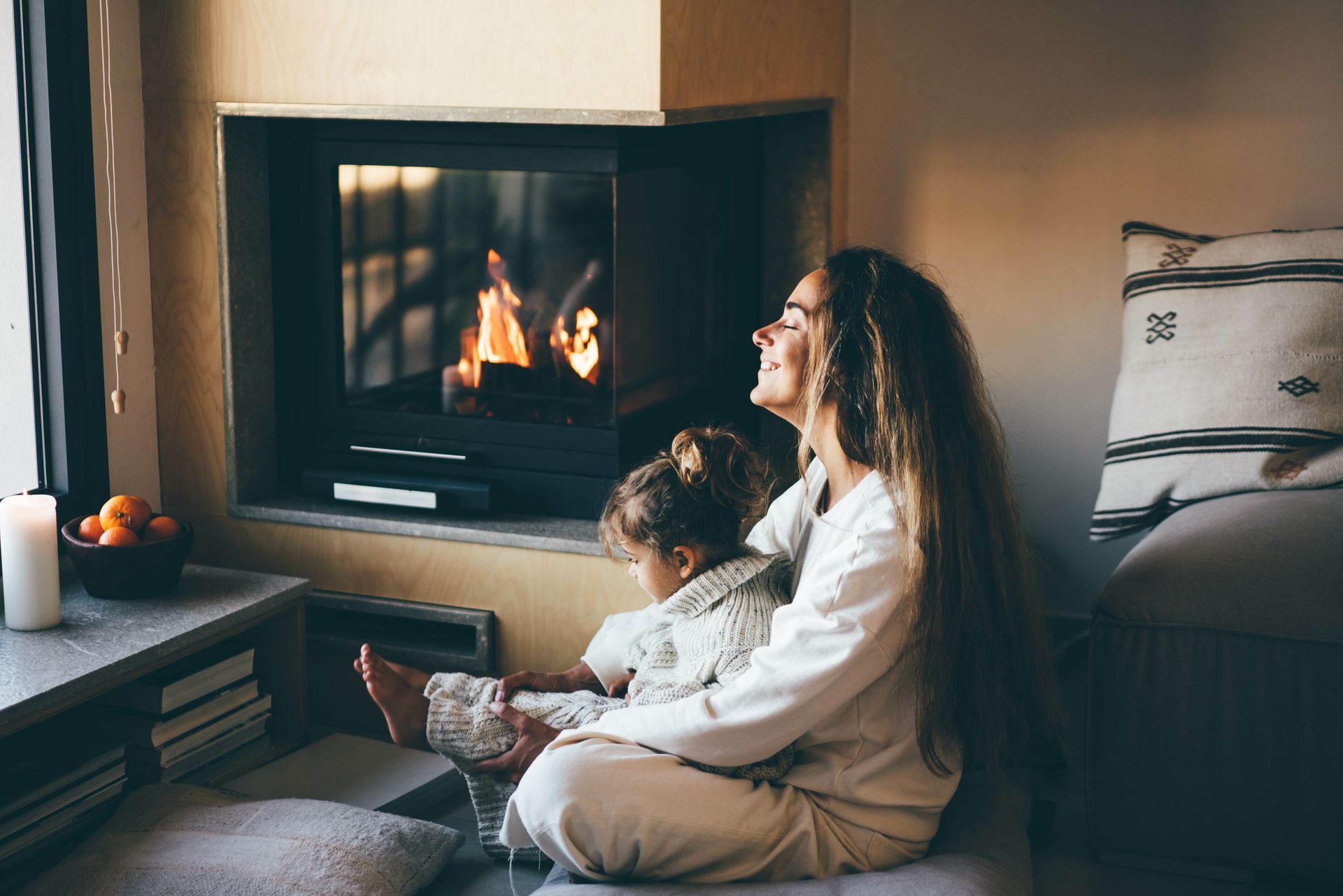 Une mère qui enlace son enfant devant un insert à bois