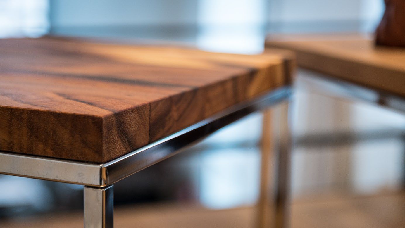 Nahaufnahme einer Tischplatte aus Holz mit Metallgestell in moderner Einrichtung.