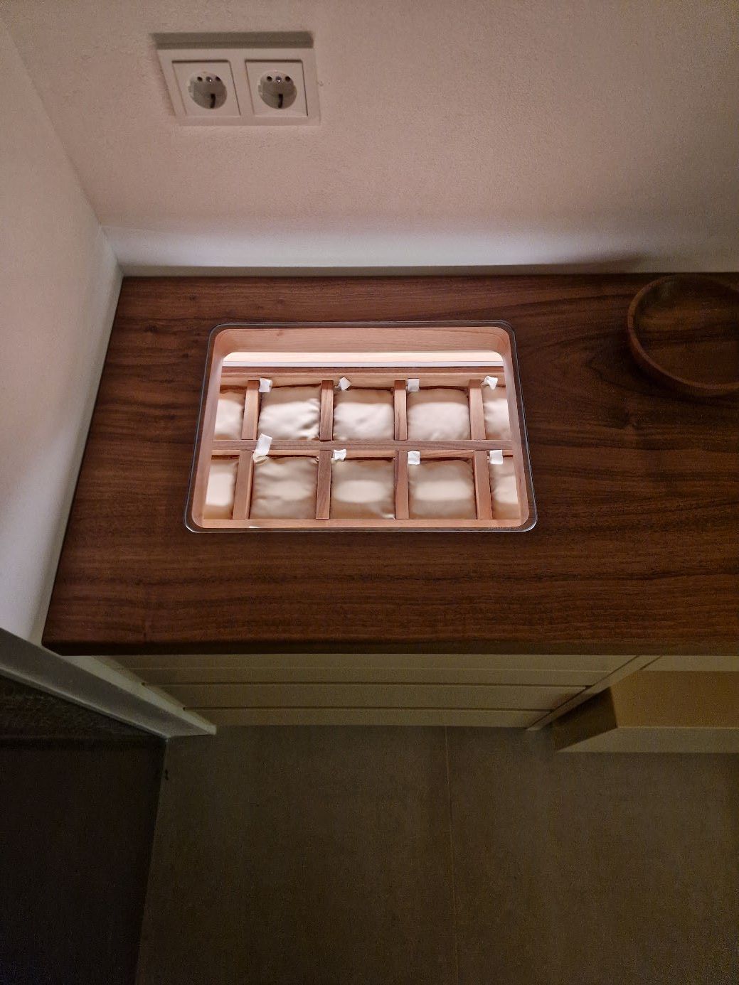 Holzarbeitsplatte mit eingelassenem rechteckigem Fach, das mit mehreren weißen Stofftaschen unterteilt ist