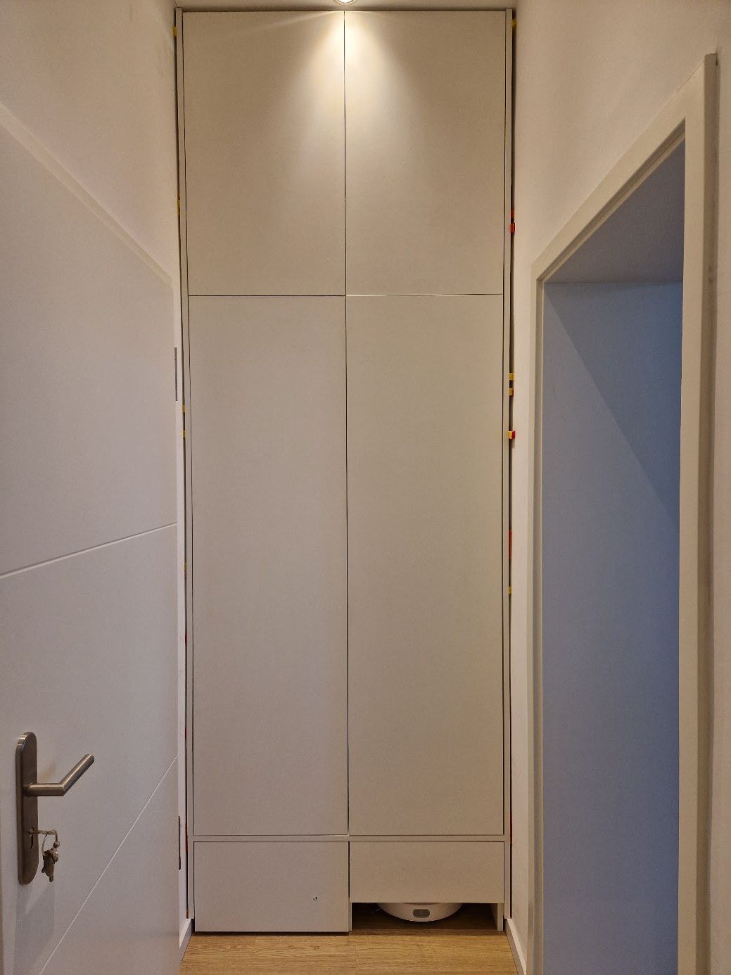 Schmaler Flur mit weißen Wänden, einer weißen Tür