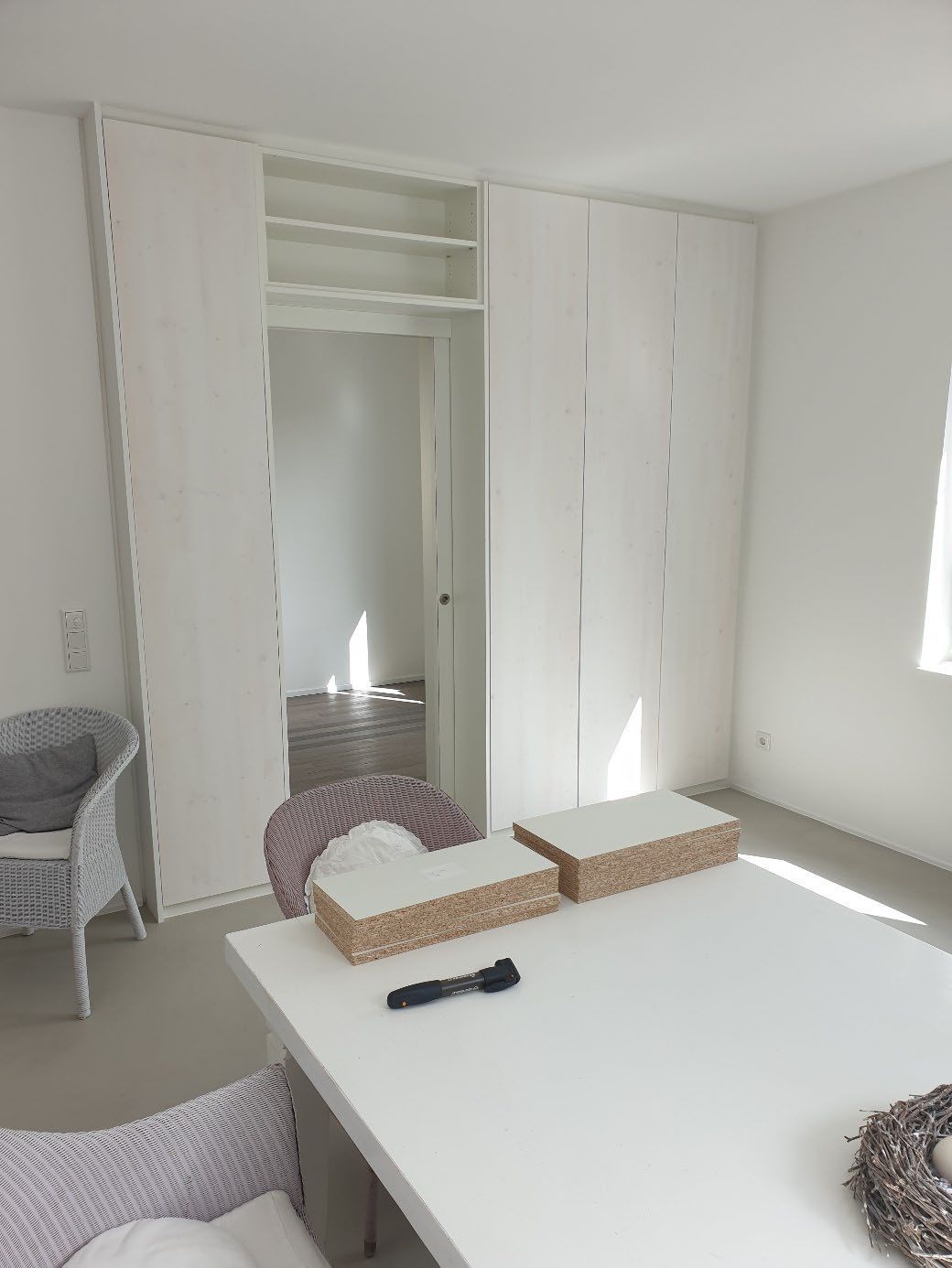 Heller Raum mit weißem Tisch, zwei gepolsterten Stühlen