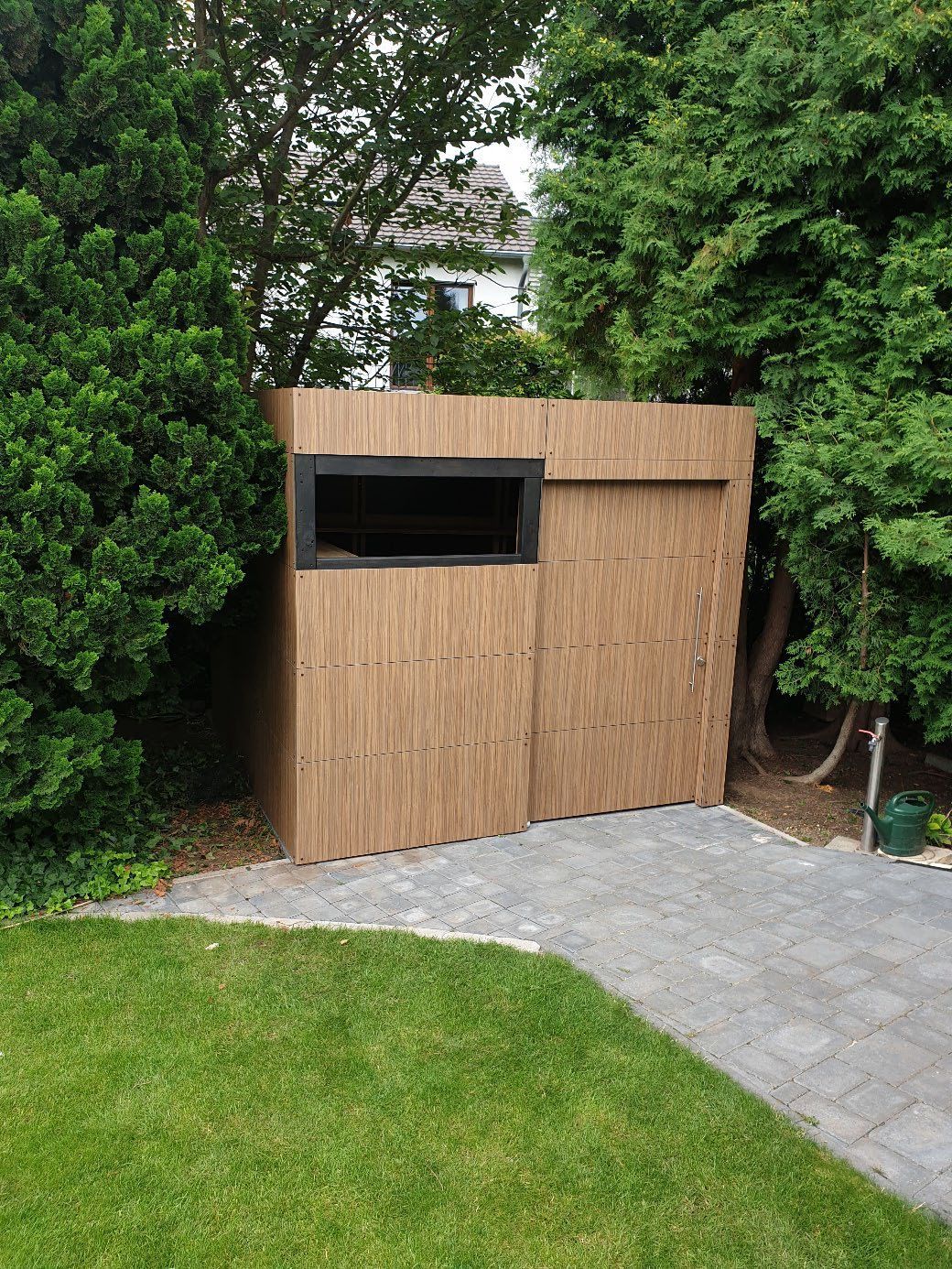 Kleines Holzgebäude eingebettet in grüne Vegetation.