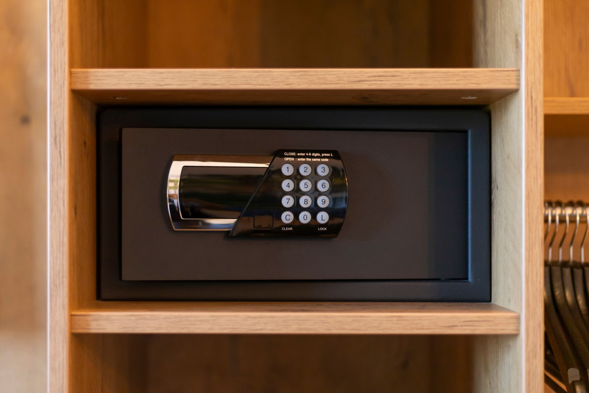 Petite serrure à clavier numérique installée dans un coffre-fort noir à l'intérieur d'une armoire en bois