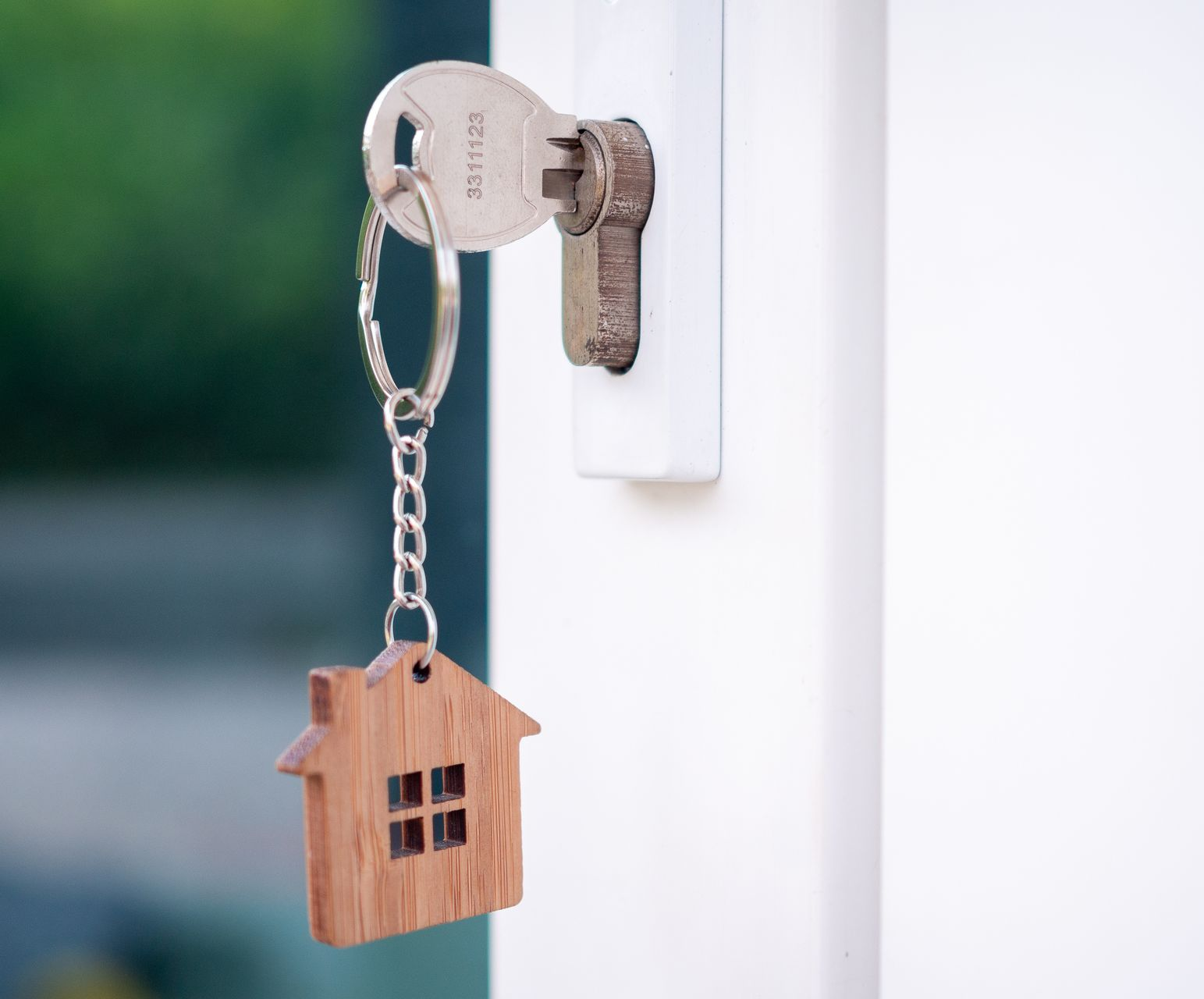 Porte-clés en forme de maison suspendu à une clé argentée dans une serrure blanche