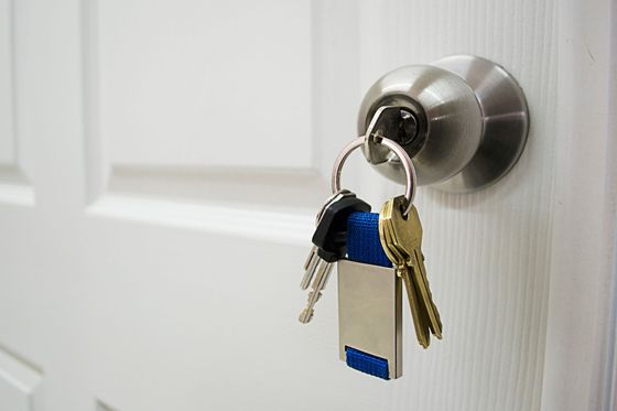 Clés sur un anneau accroché à une poignée de porte argentée sur une porte blanche