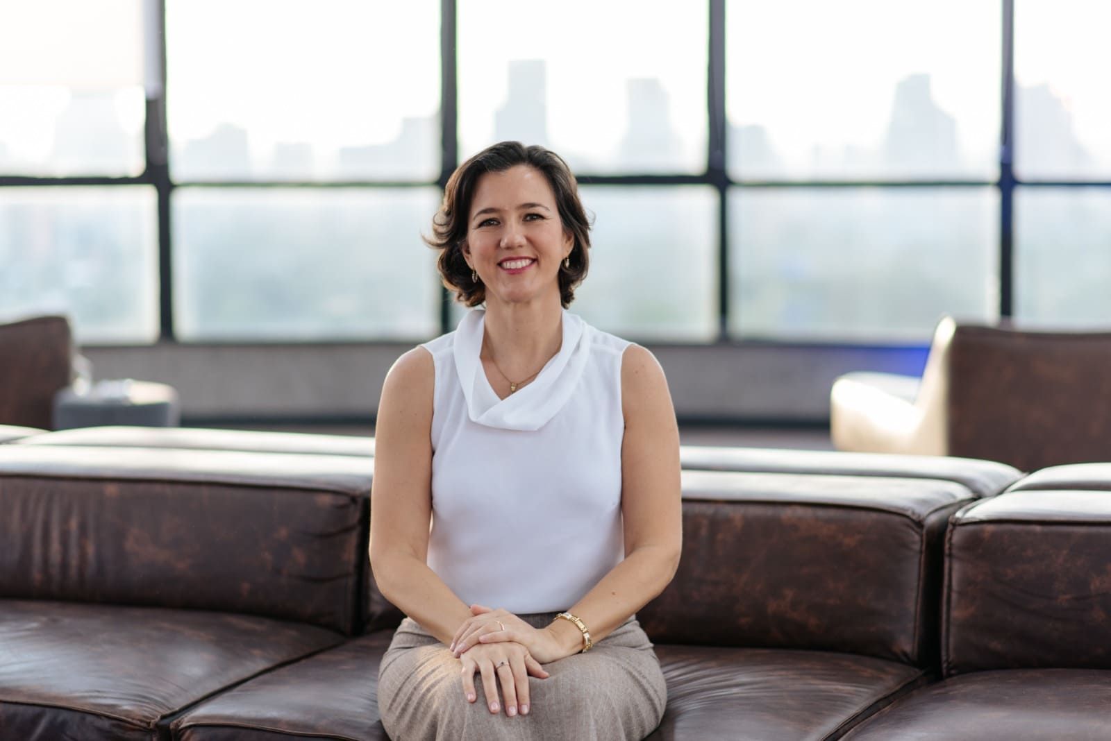 Una mujer está sentada en un sofá frente a una ventana.