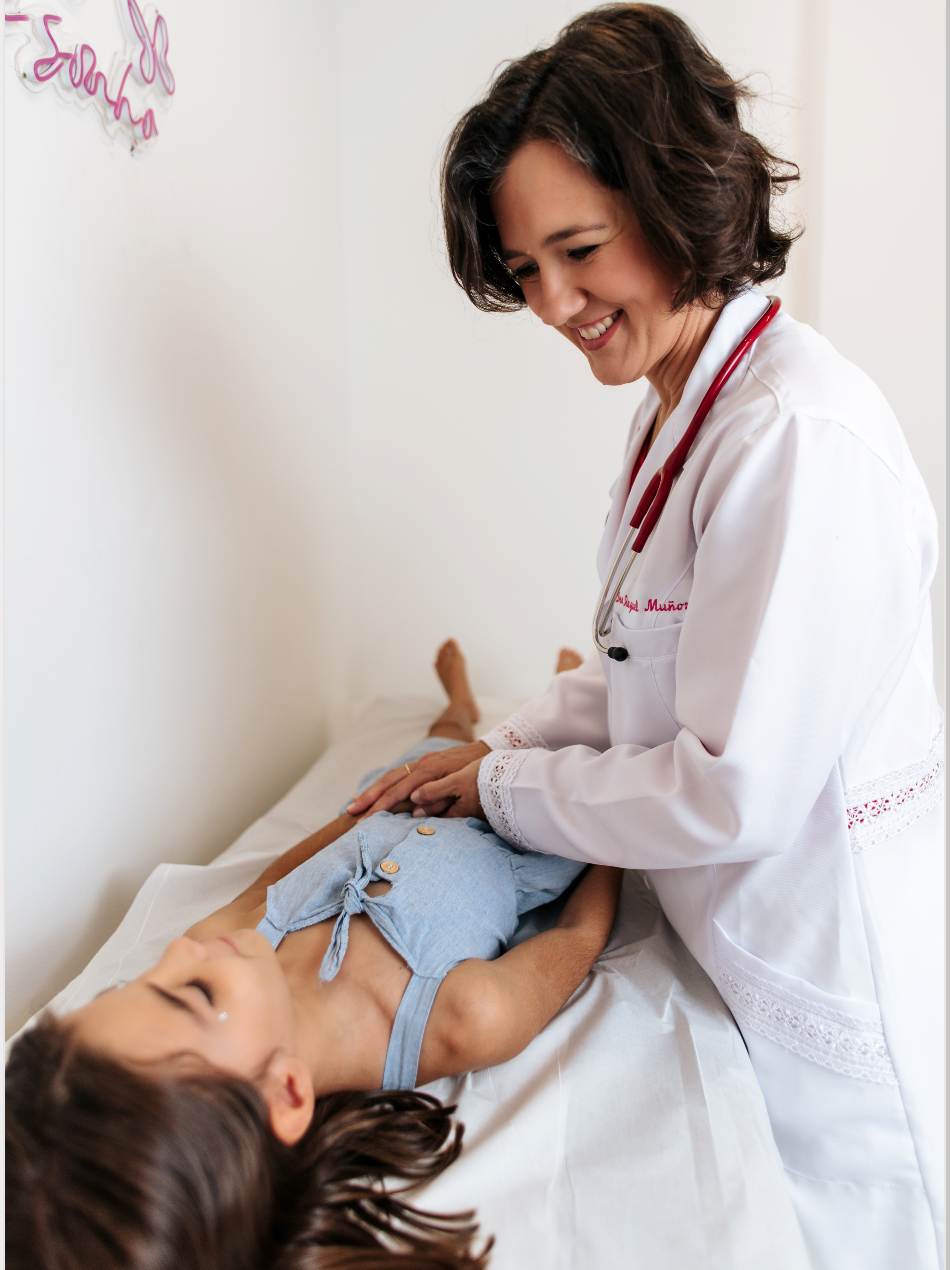 Un médico está examinando a una niña acostada en una mesa.