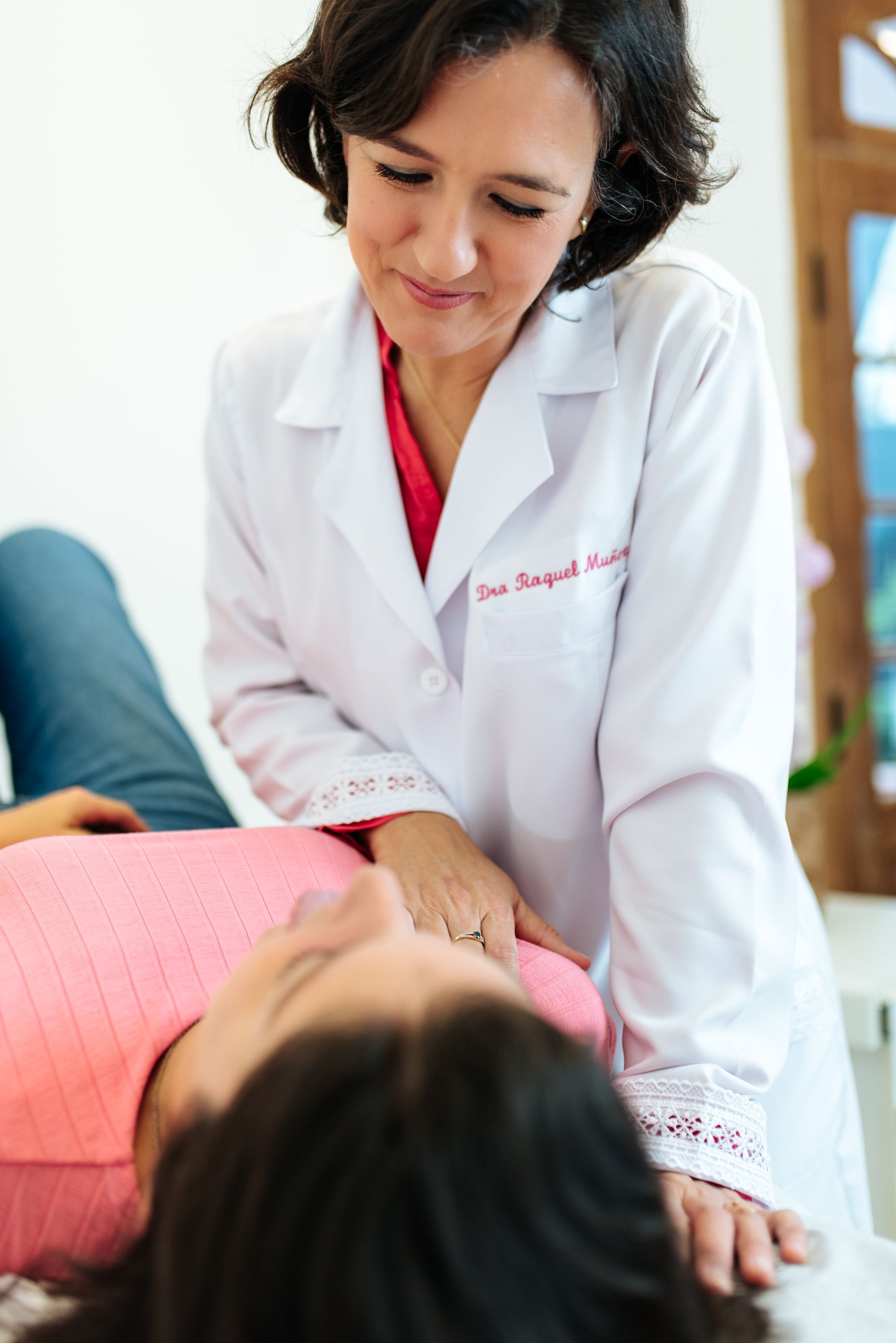 Una mujer con una bata blanca examina el estómago de una mujer.