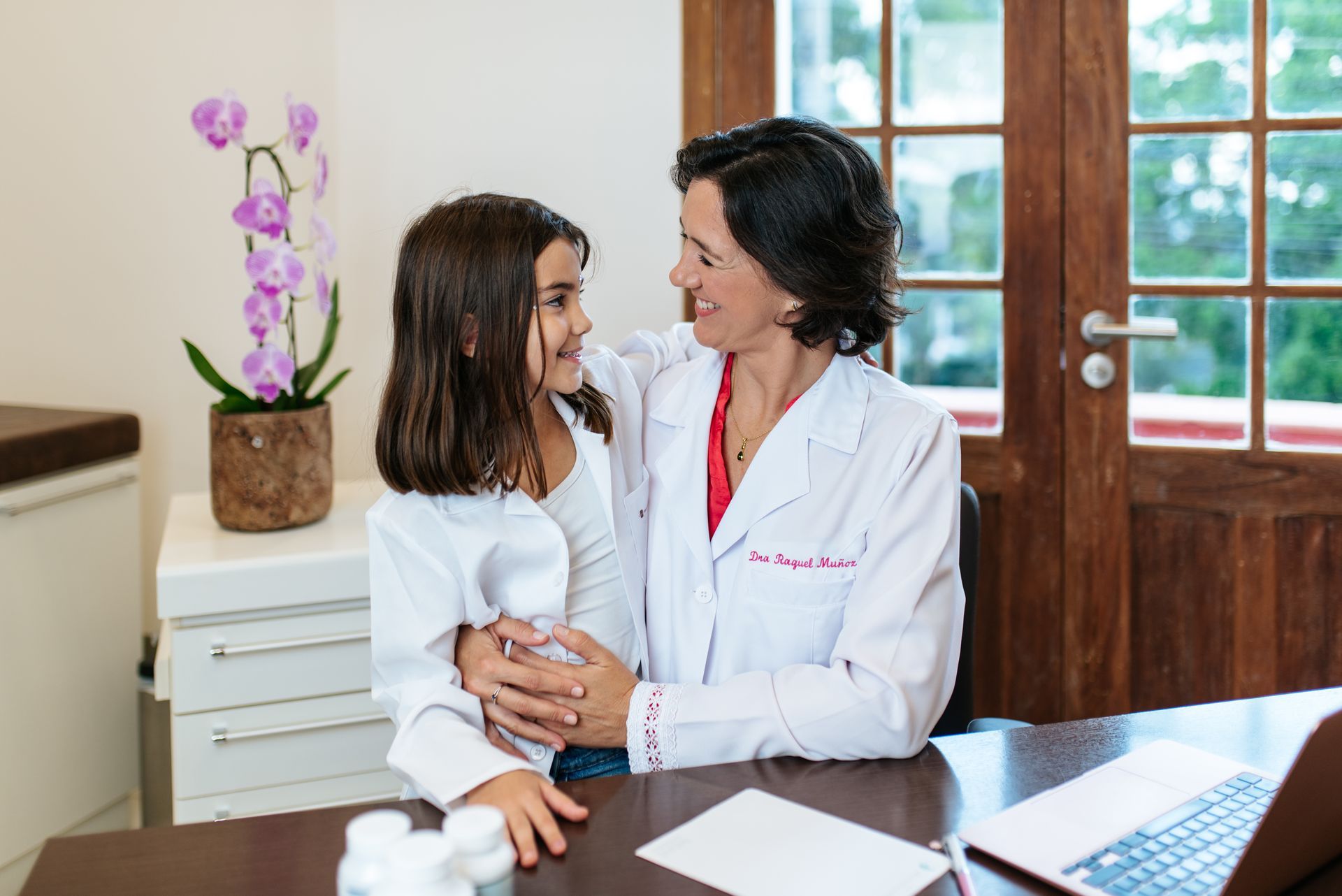 Un médico está sentado en un escritorio sosteniendo a una niña.