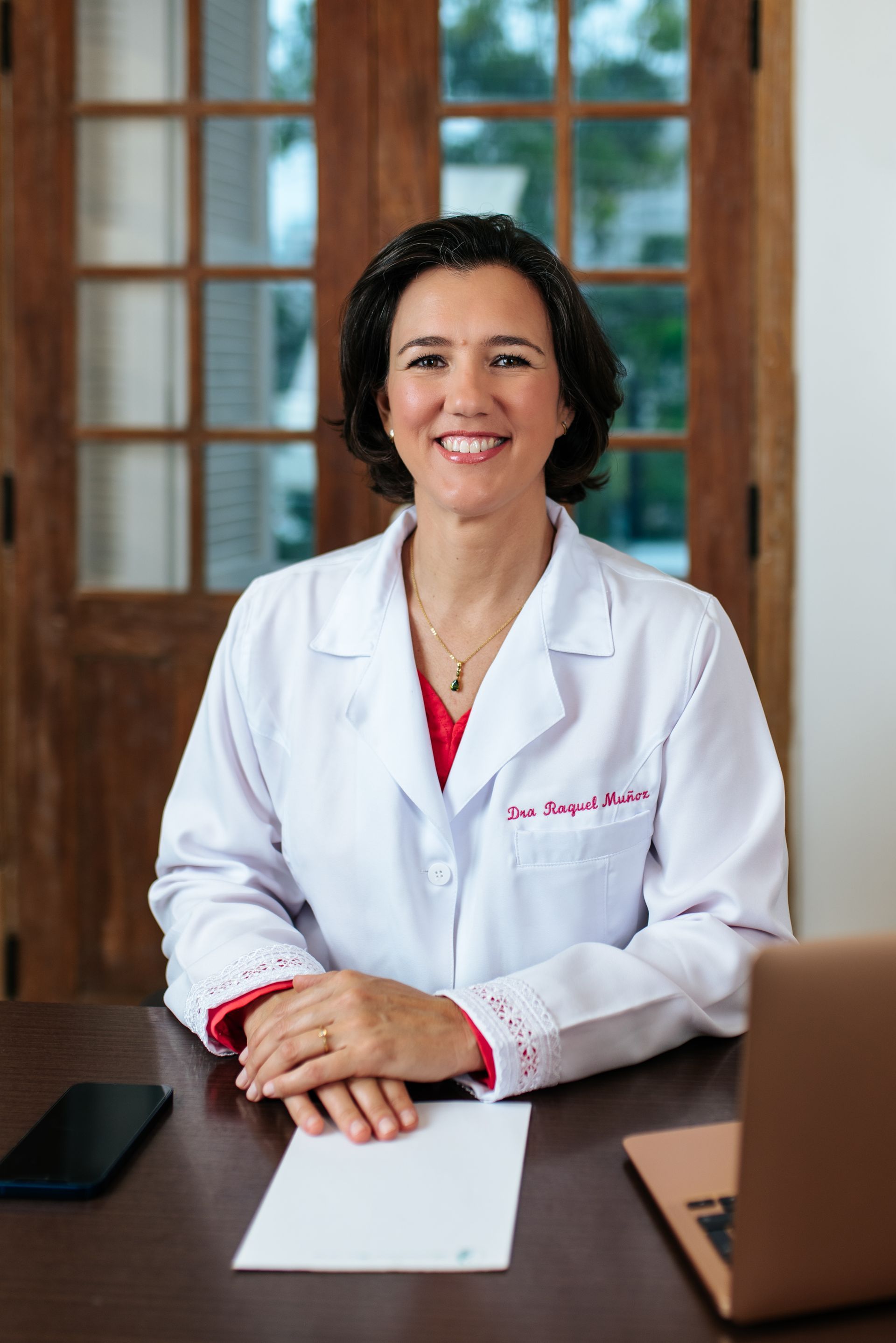 Una mujer con una bata de laboratorio está sentada en un escritorio con una computadora portátil.