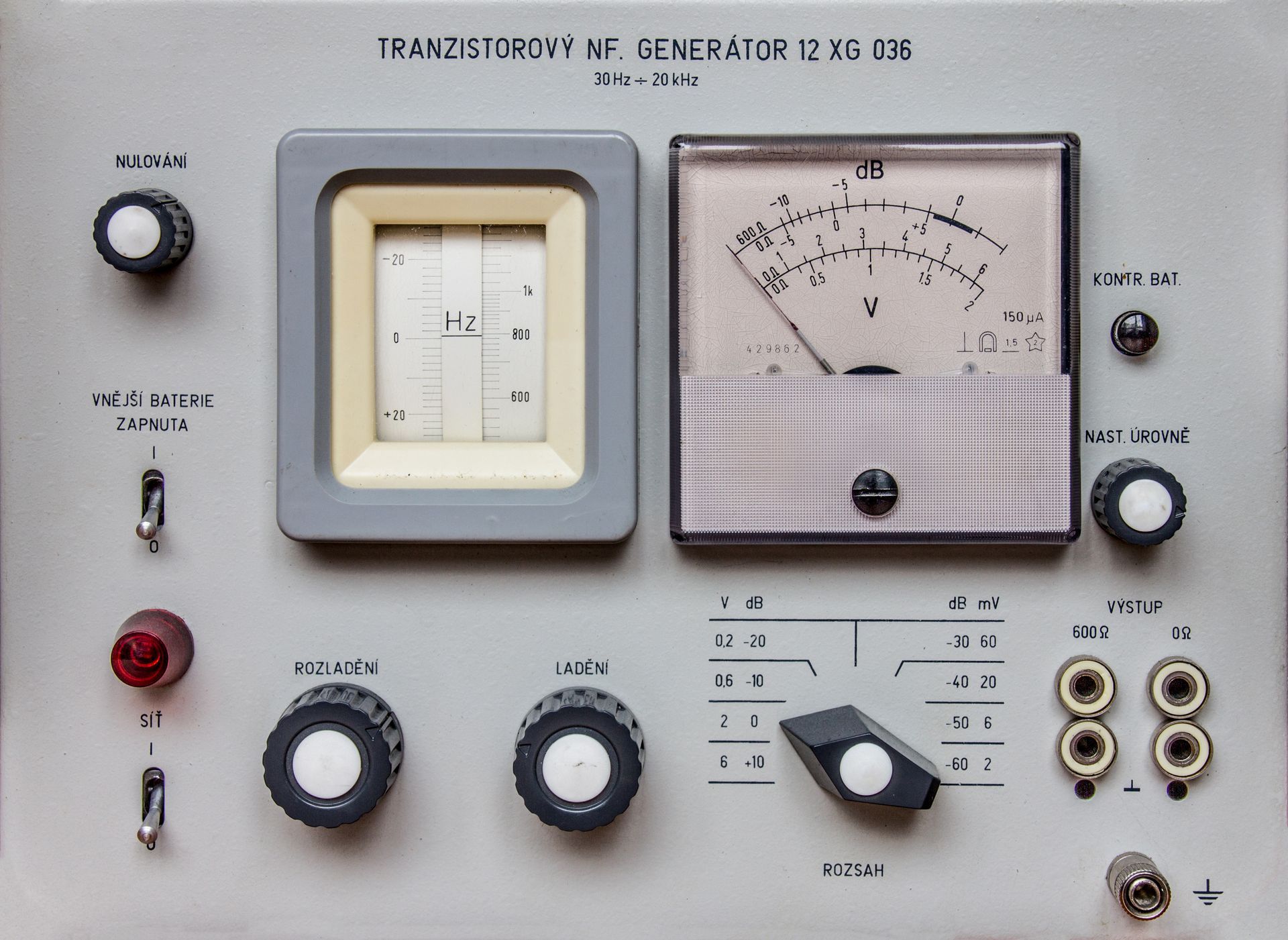 Panneau de commande électronique vintage avec des appareils de mesure analogiques, des boutons, des interrupteurs et des prises sur une façade.