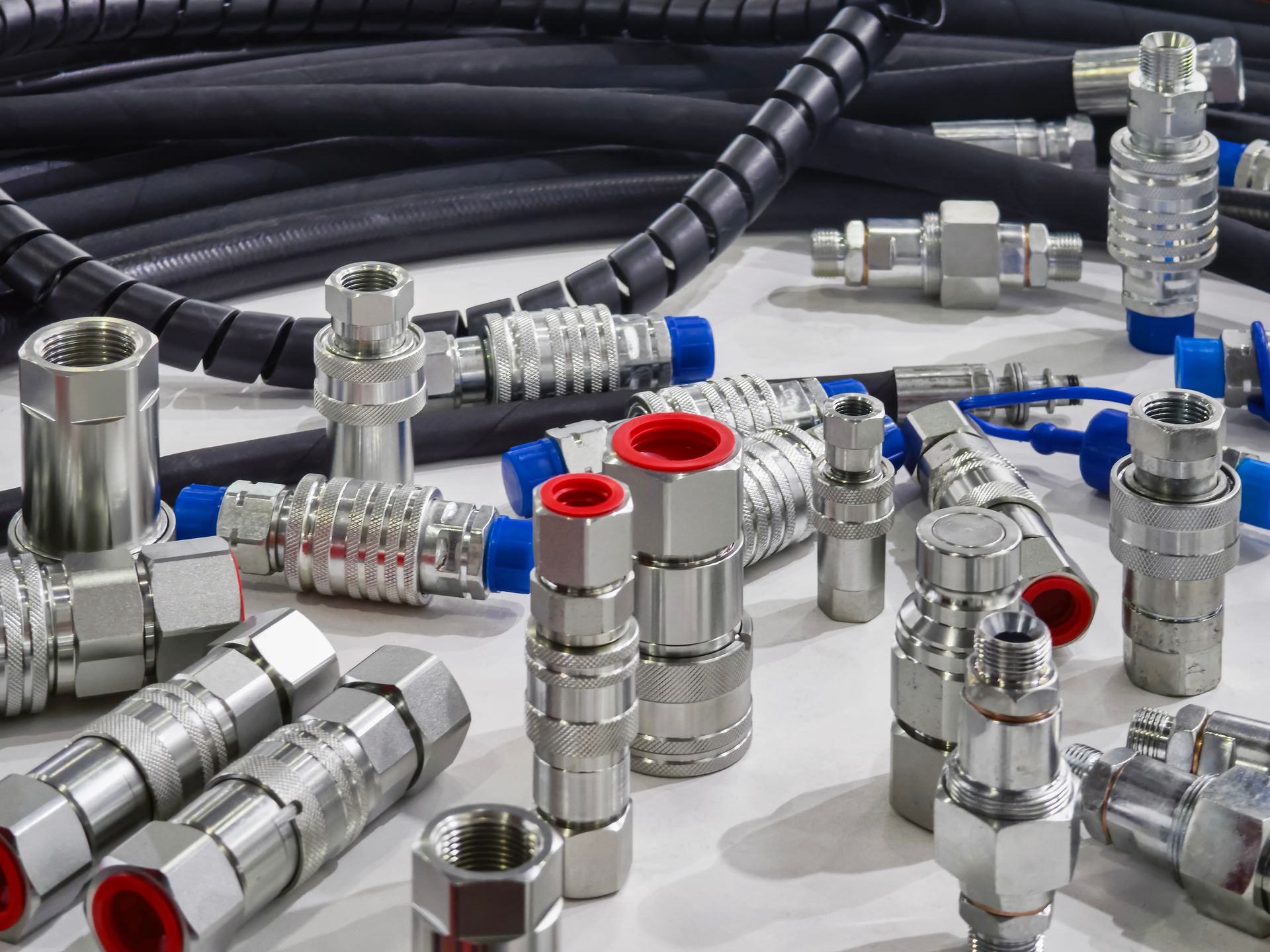 Différents raccords et connecteurs métalliques pour flexibles hydrauliques, avec des bouchons.