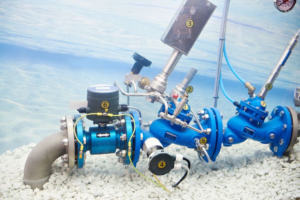 Ensemble de vanne industrielle immergée dans une eau limpide, raccordé à une grosse conduite.