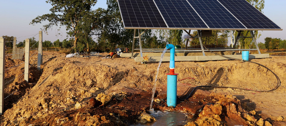 Des panneaux solaires alimentant une pompe à eau dans un champ sec et boueux.