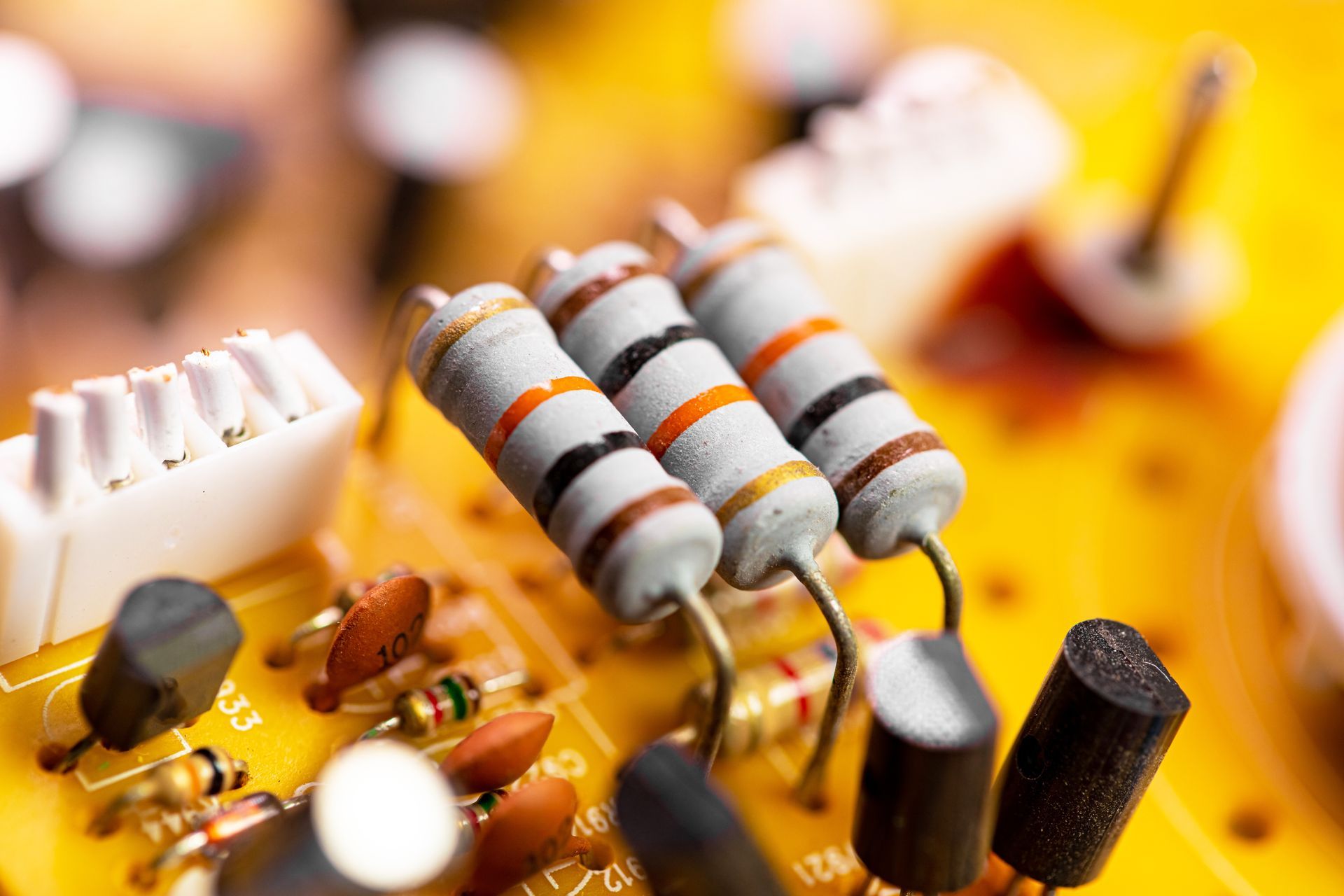 Gros plan de composants électroniques sur une carte de circuit imprimé, notamment des résistances, des condensateurs et des connecteurs.