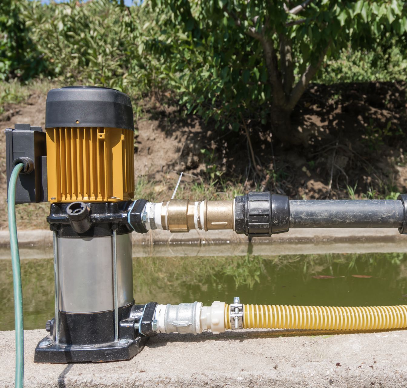 Pompe à eau avec un moteur relié à des tuyaux, au bord d’un étang.