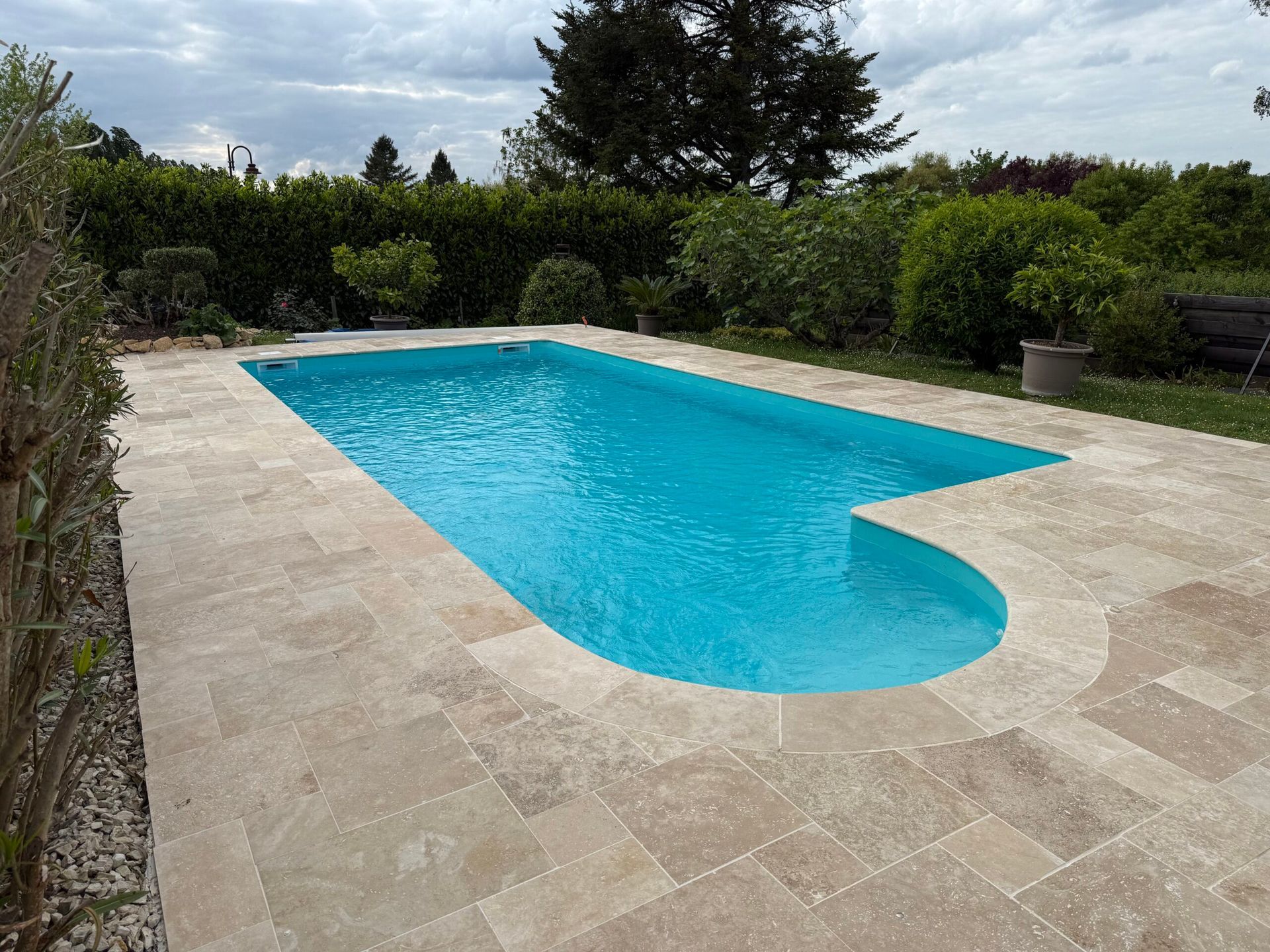 Piscine extérieure avec une eau turquoise, une terrasse en pierre et une végétation luxuriante tout autour