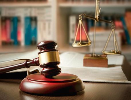 El mazo de un juez y la balanza de la justicia están sobre una mesa de madera.