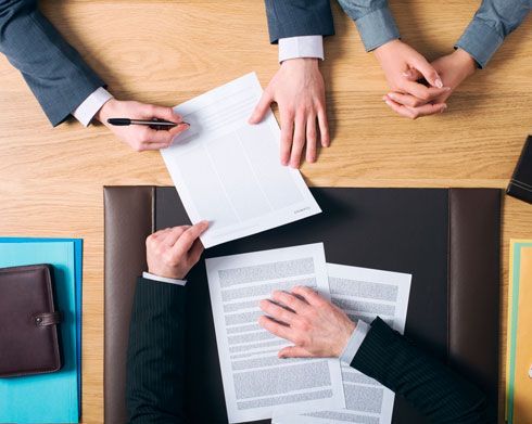 Un grupo de personas está sentada en una mesa firmando un documento.
