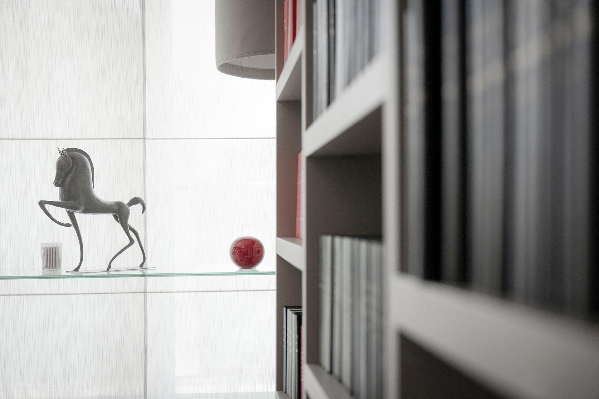 Un homme en costume est assis à un bureau dans une bibliothèque et lit un livre.
