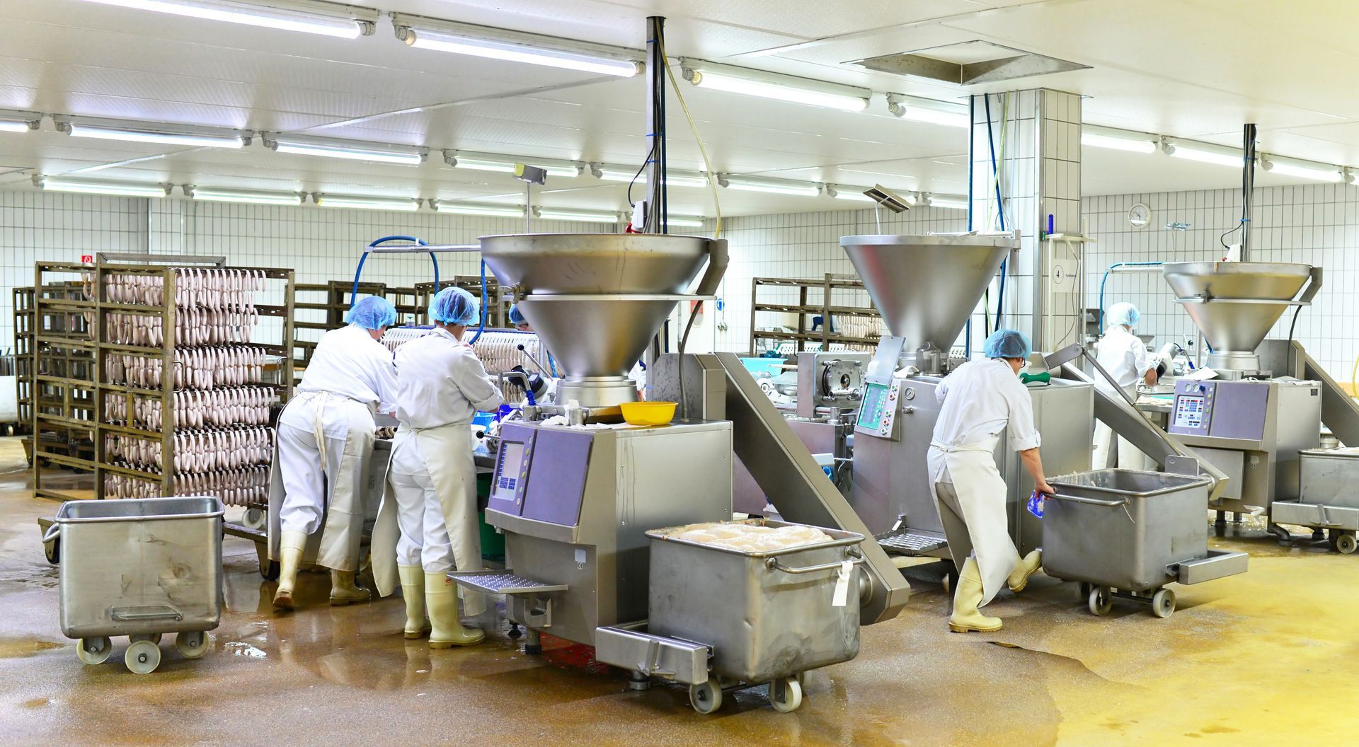 Des ouvriers vêtus de combinaisons de protection blanches actionnent des machines de transformation alimentaire dans une installation industrielle stérile.