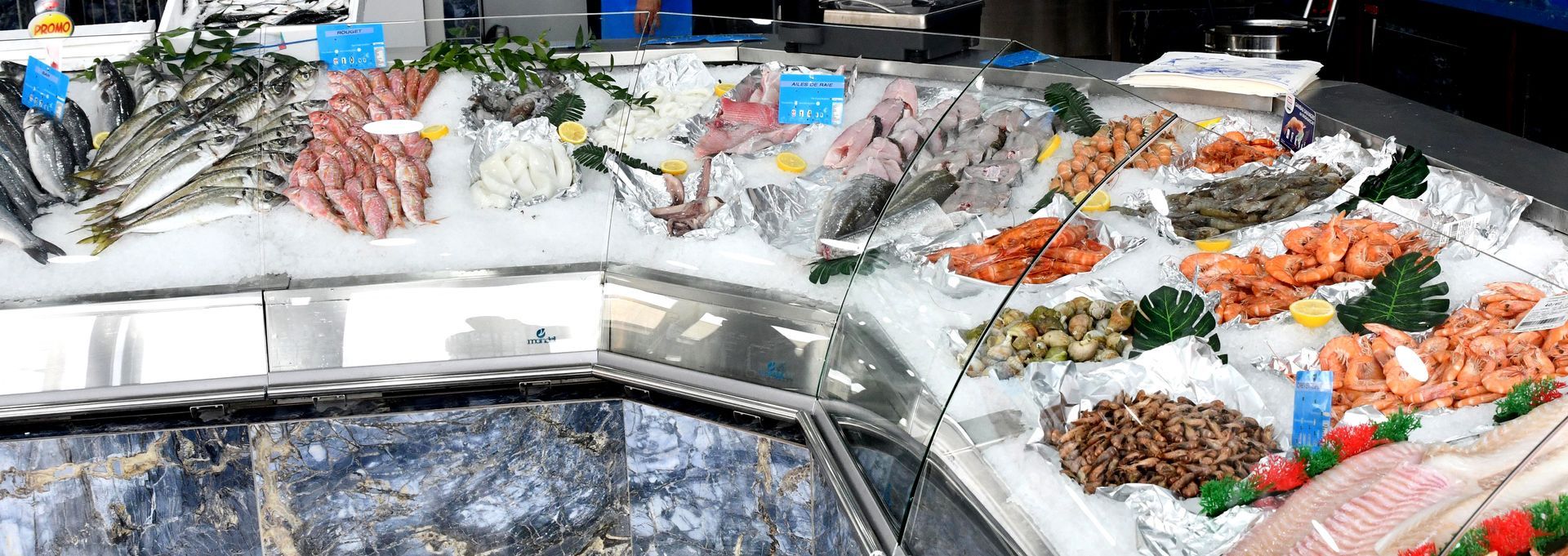 Un étalage de poissons et de fruits de mer frais variés, disposés sur un lit de glace, sur un comptoir de marché.
