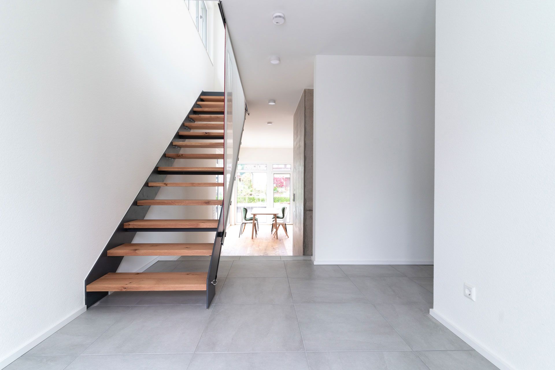 ein leerer Flur mit einer Holztreppe , die zum zweiten Stock führt .