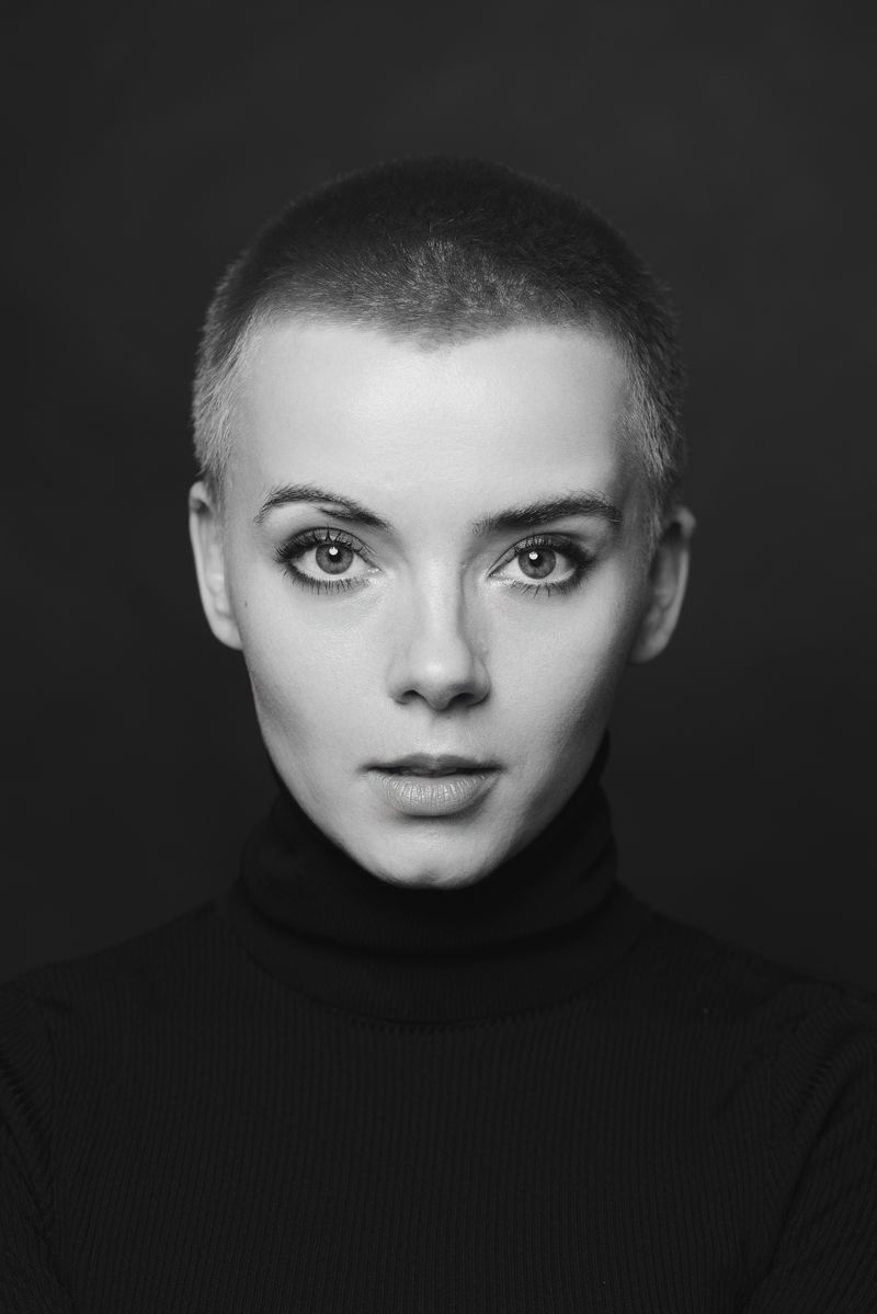 Ein Schwarzweißfoto einer Frau mit sehr kurzen Haaren, die einen Rollkragenpullover trägt.