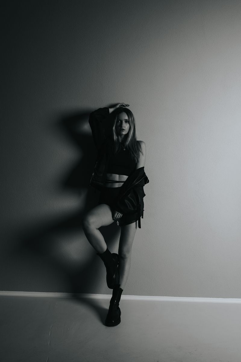 Ein Schwarzweißfoto einer Frau, die vor einer Wand steht.