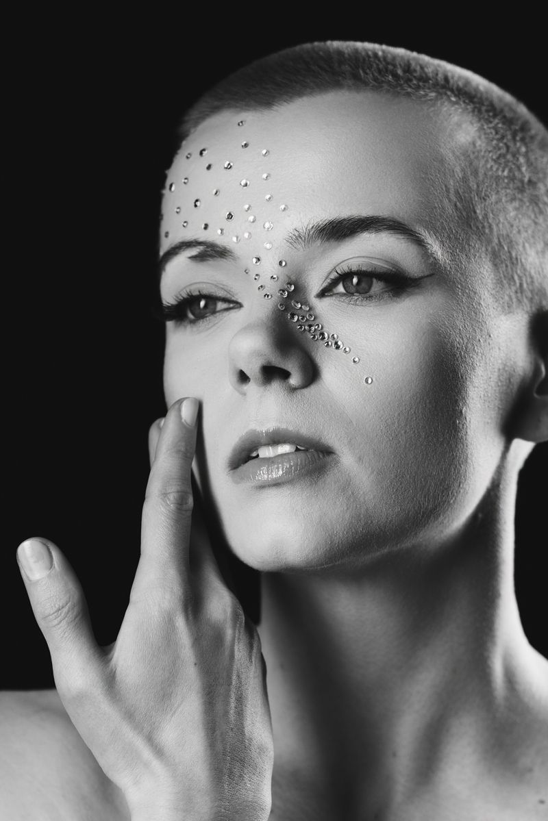 Auf einem Schwarzweißfoto berührt eine Frau mit rasiertem Kopf ihr Gesicht.