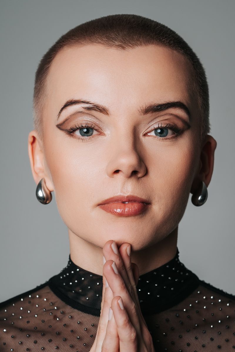 Eine Nahaufnahme des Gesichts einer Frau, die die Hände vor dem Gesicht gefaltet hat.