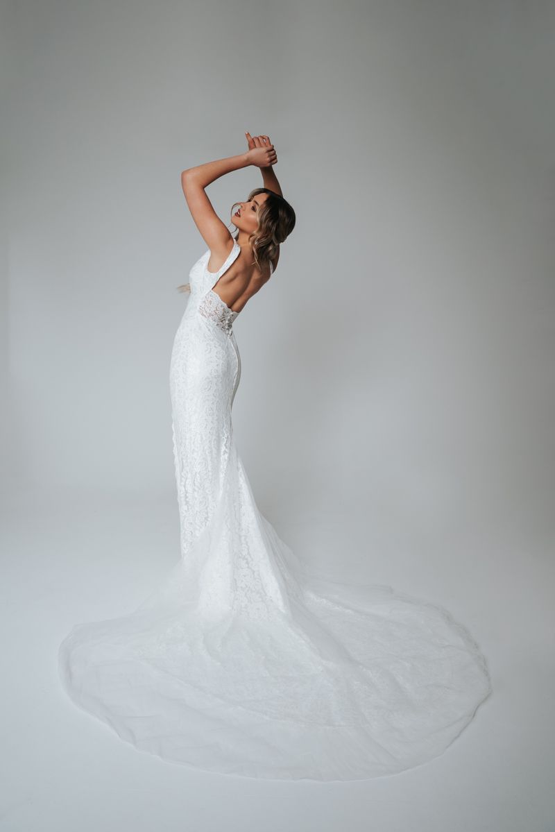 Eine Frau in einem weißen Brautkleid steht vor einem weißen Hintergrund.