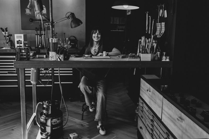 Auf einem Schwarzweißfoto sitzt eine Frau an einem Schreibtisch.