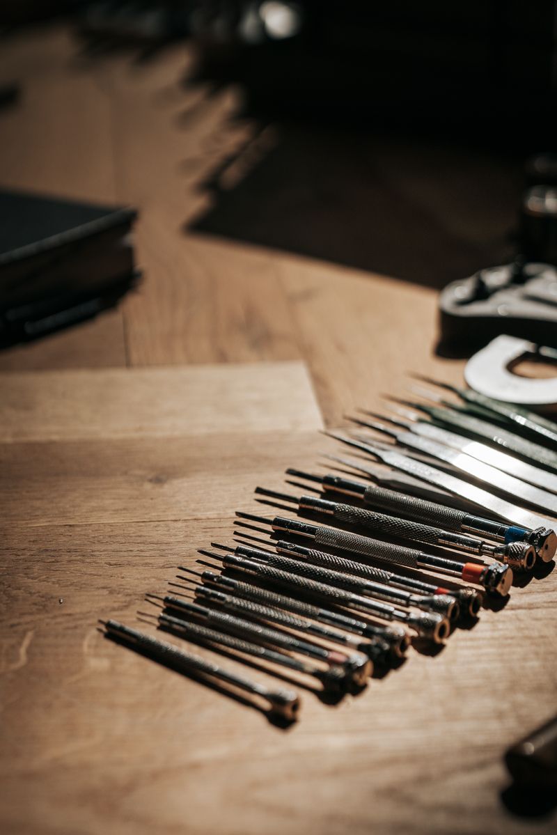 Auf einem Holztisch liegt ein Haufen Schraubenzieher.