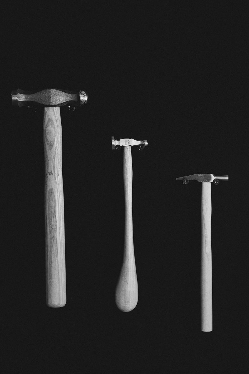 Auf schwarzem Hintergrund sind drei Hämmer in einer Reihe aufgereiht.