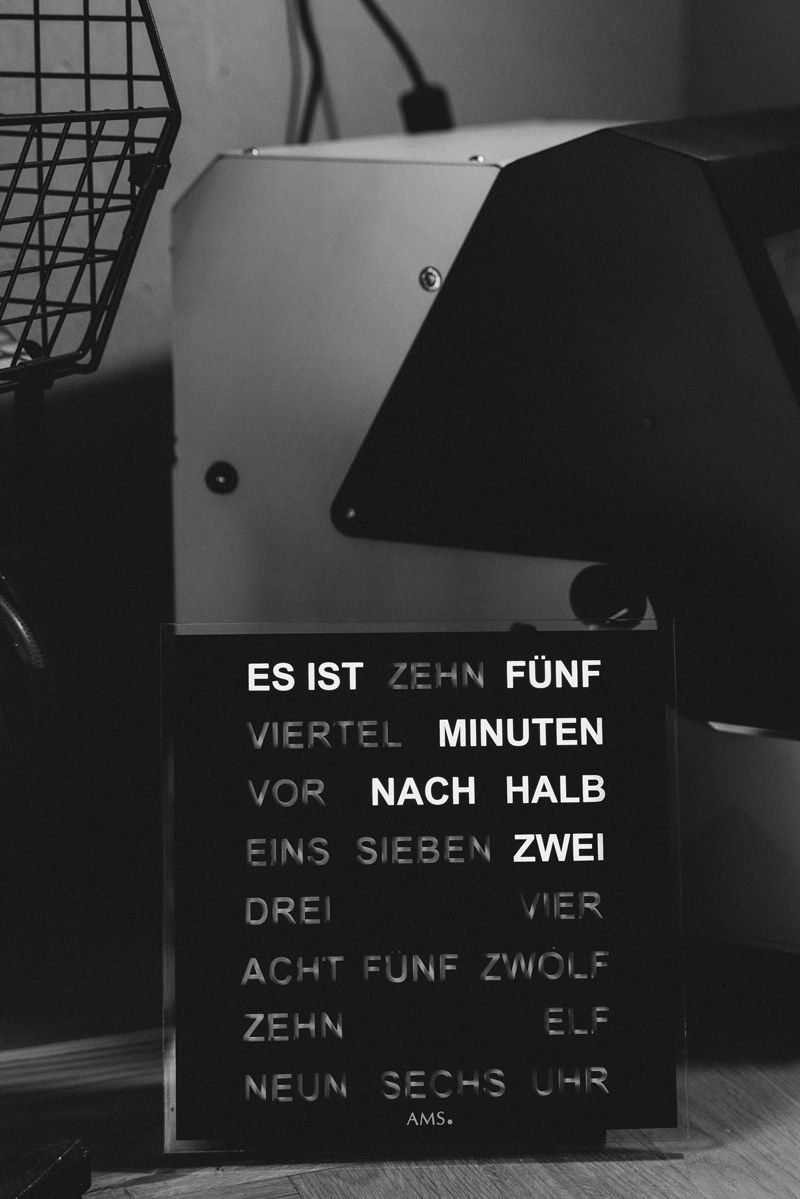 Ein Schwarzweißfoto eines Schildes mit der Aufschrift „Es ist zehn fonf“
