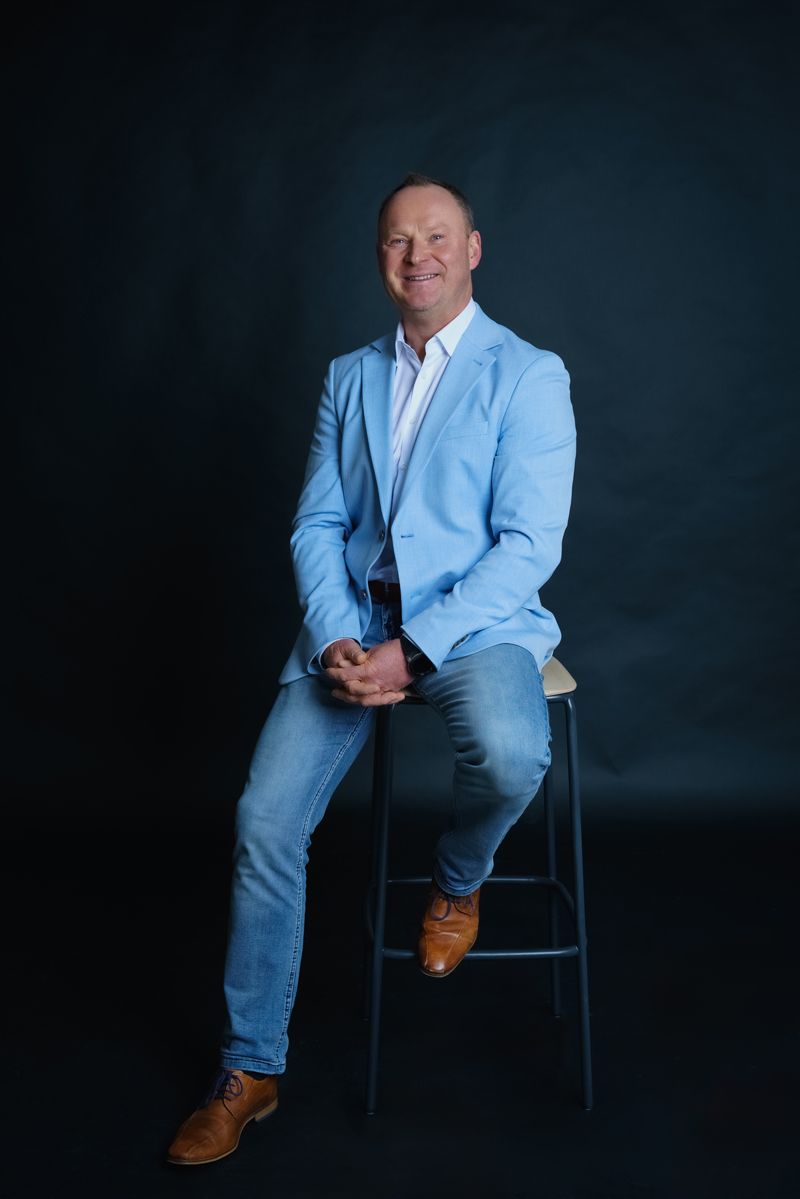 Ein Mann in einem blauen Anzug sitzt auf einem Barhocker.