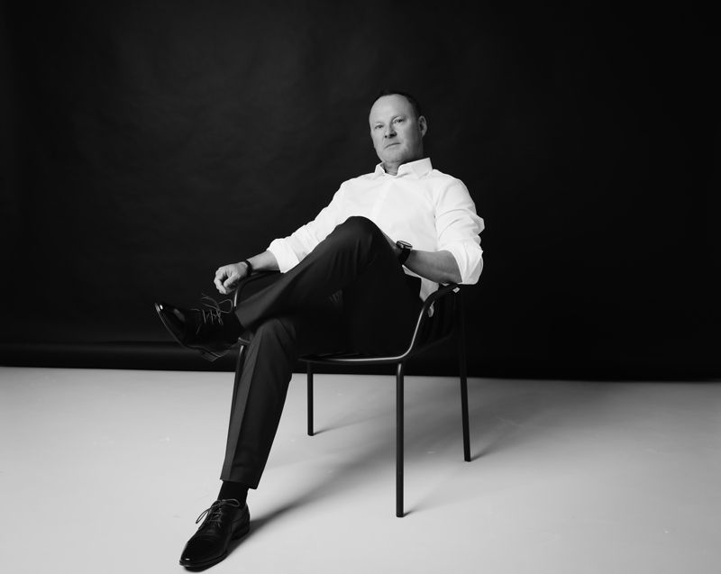 Ein Mann sitzt mit gekreuzten Beinen auf einem Stuhl