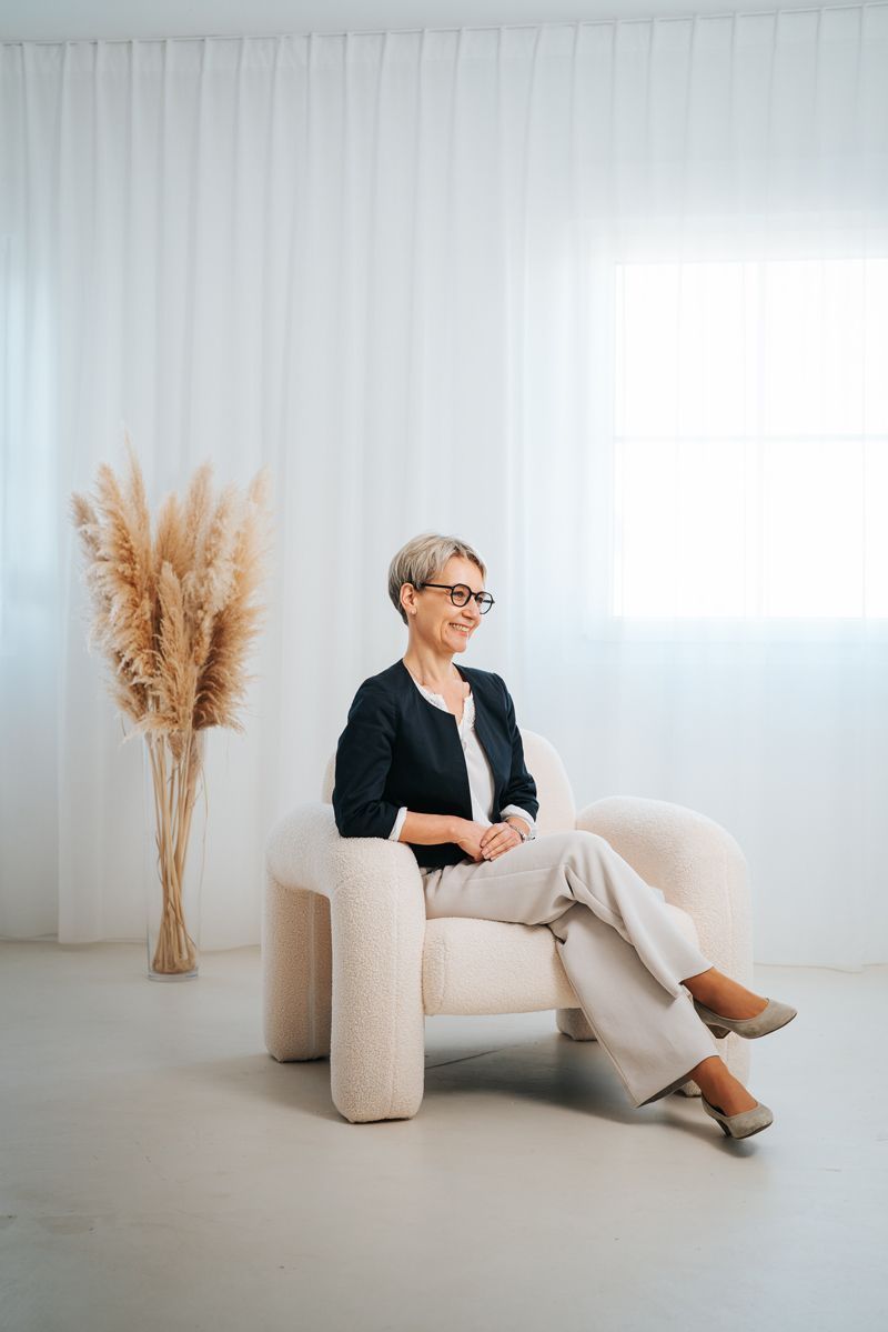 Eine Frau sitzt auf einem Stuhl vor einem Fenster.