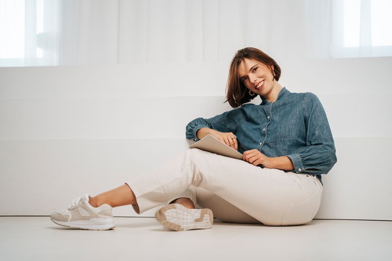 Eine Frau sitzt auf dem Boden und benutzt einen Tablet-Computer.