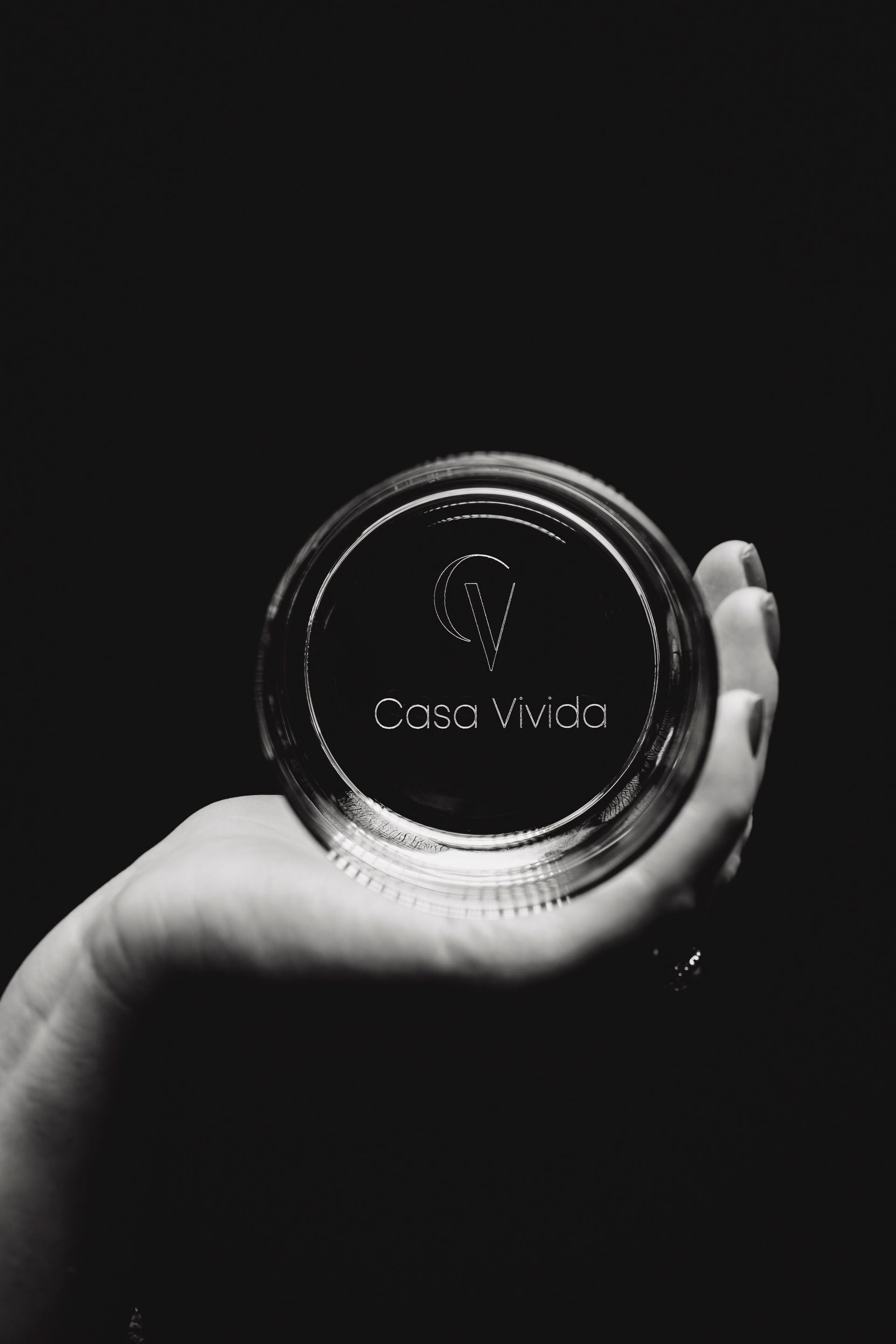 Ein Schwarzweißfoto einer Person, die ein Glas in der Hand hält.