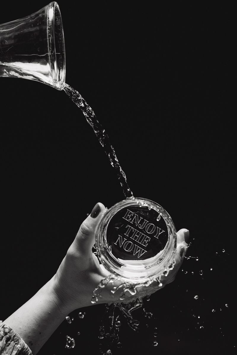 Ein Schwarzweißfoto einer Person, die Wasser in ein Glas gießt