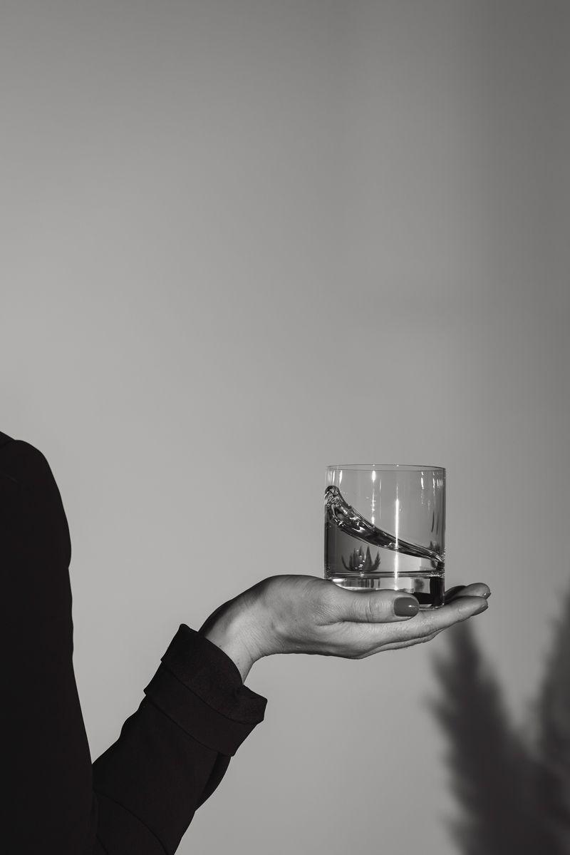 Eine Person hält ein Glas Wasser in der Hand.