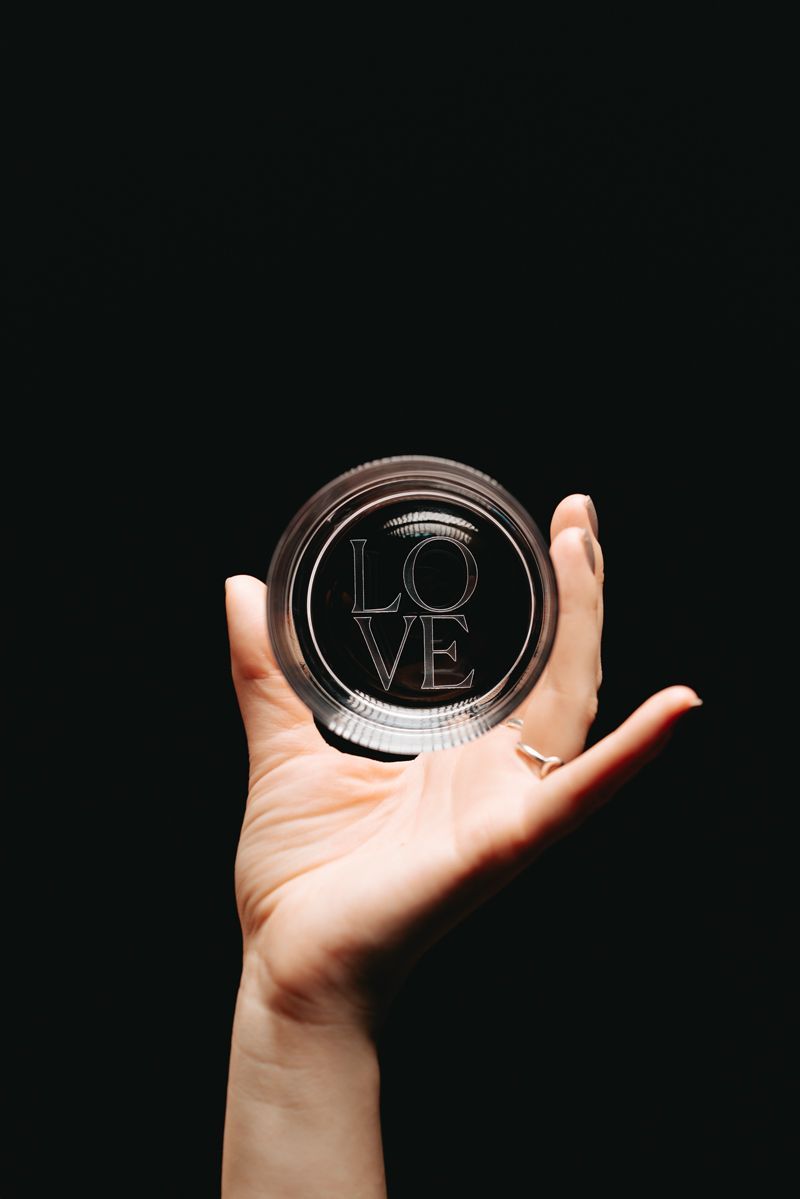 Eine Person hält eine Glaskugel mit dem Wort „Liebe“ darauf.