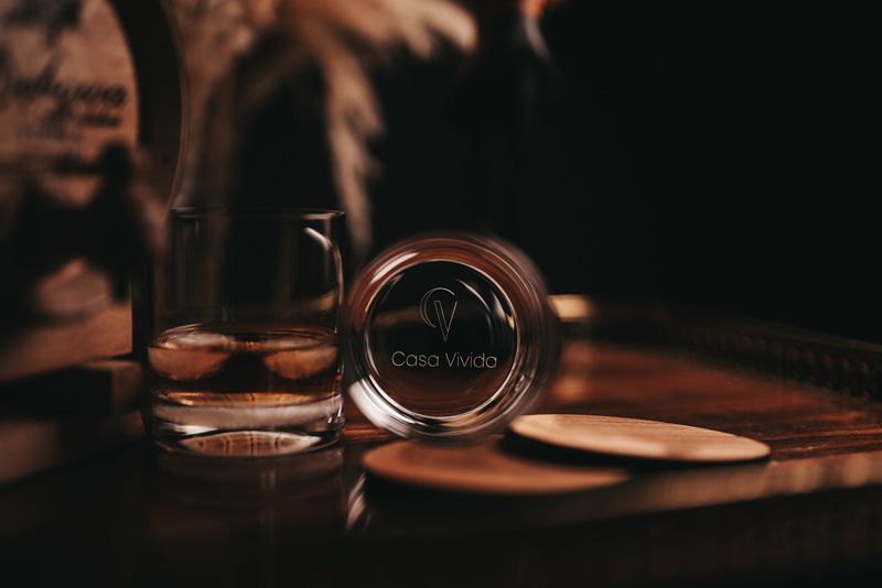 Auf einem Holztisch steht neben einem Untersetzer ein Glas Whisky.