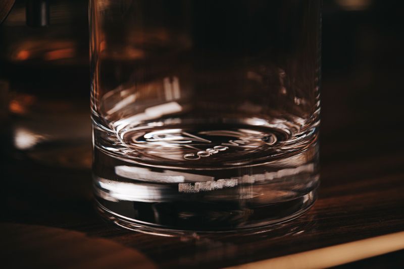 Auf einem Holztisch steht ein Glas Wasser.