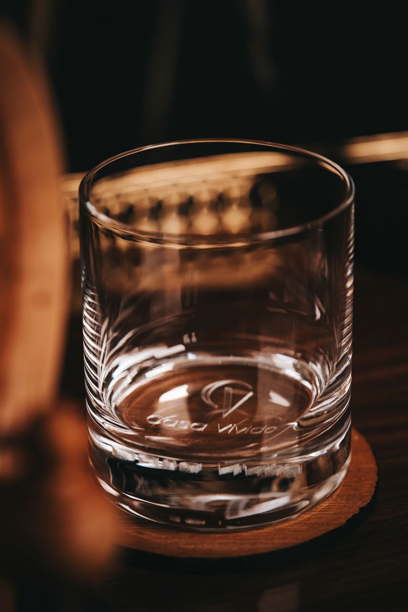 Ein Glas Whisky steht auf einem Holzuntersetzer auf einem Tisch.