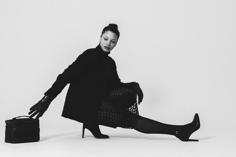 Ein Schwarzweißfoto einer Frau, die mit übereinandergeschlagenen Beinen auf dem Boden sitzt.