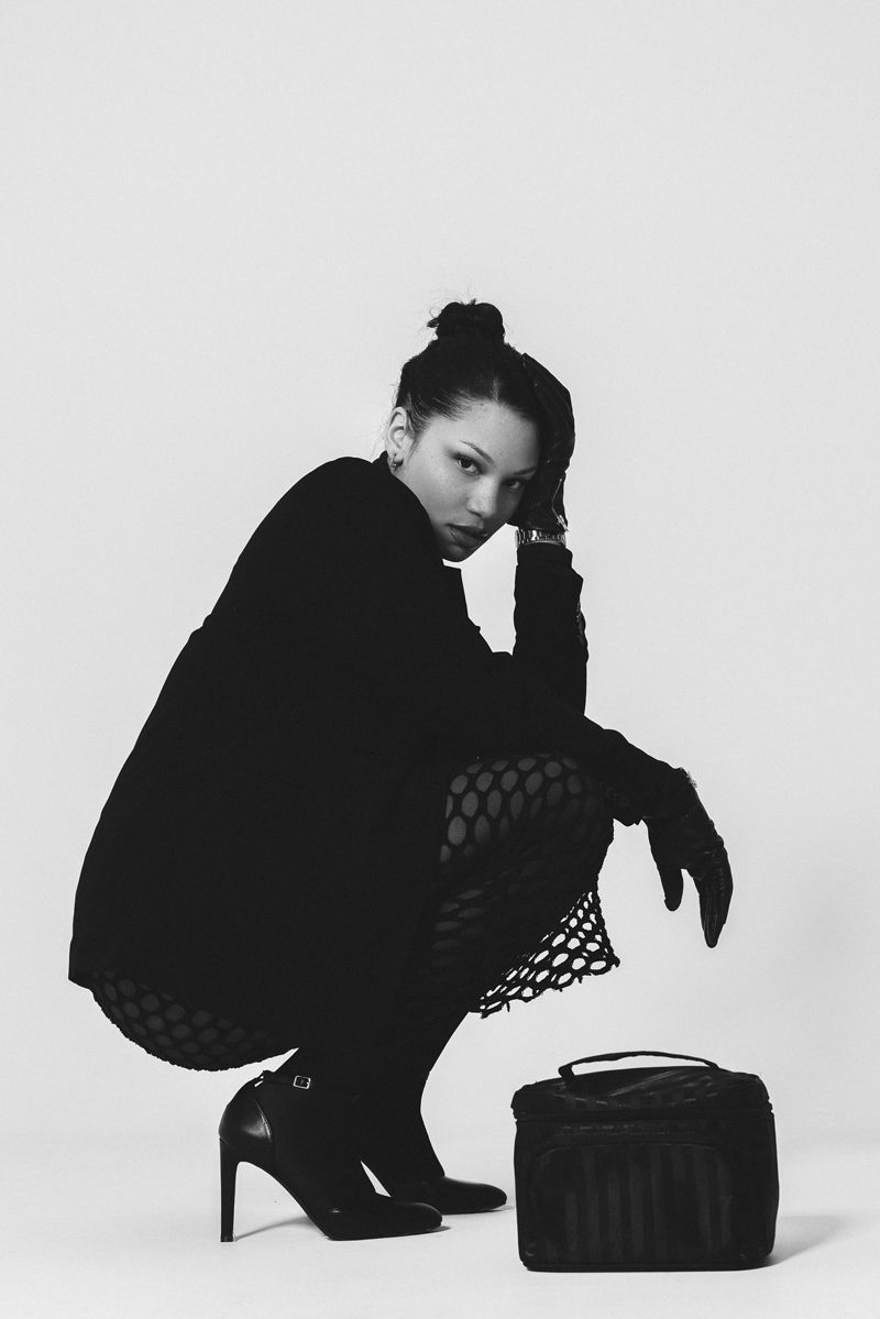 Ein Schwarzweißfoto einer Frau, die neben einer Handtasche hockt